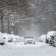 A car drives down a snow-covered road